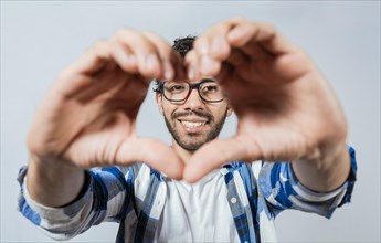 Person putting hands together in a heart shape. Teenage guy making heart shape with hands isolated. Happy man making heart shape with hands isolated