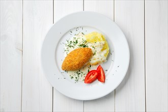 Top view of cutlet stuffed with cheese with mashed potato on white wooden table