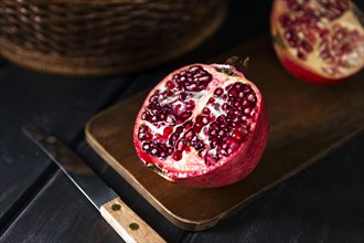 High angle autumn pomegranate halves with knife chopping board