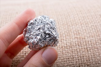 Aluminium foil in the shape of a sphere on a textured background
