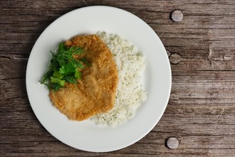 Top view of chicken fillet in breading with rice on wooden table