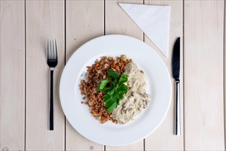 Top view of beef stroganoff with creamy onion sauce and buckwheat with fried mushrooms on served table