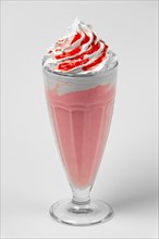 Watermelon and cherry milkshake summer cocktail in tall facetted glass on gray background