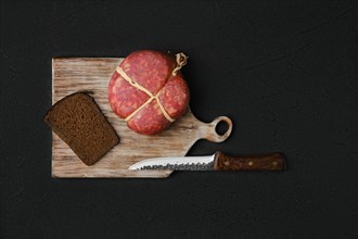 Overhead view of smoked round beef sausage on cutting board over black background