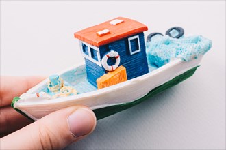 Little colorful model fishing boat in hand on white