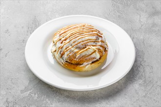 Fresh cinnamon bun with sugar icing and caramel