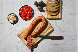 Overhead view of smoked beef sausage rings on wooden cutting board on kitchen table