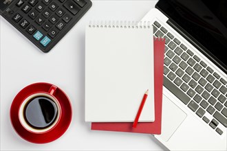 Red coffee cup calculator spiral notepad pencil laptop white background