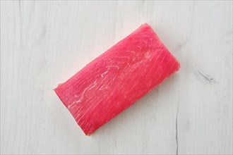 Raw frozen tuna fillet on wooden background