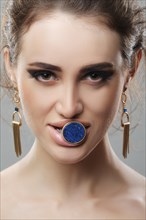 Portrait of beautiful fashion model with finger ring with big stone in her mouth. Fresh skin and natural makeup