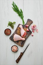 Overhead view of raw chicken legs on wooden cutting board ready for cooking