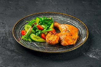 Baked chicken thigh served with fresh vegetables and grilled corn on dark background