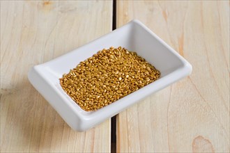 Top view of gold plated sesame seeds in cepamic bowl