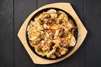 Overhead view of slices of eggplant baked with champignon and cheese in cast iron skillet