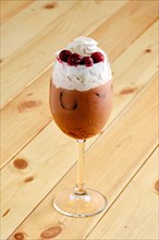 Cold raf coffee with cherry in transparent glass on wooden background