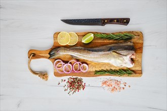 Fresh gutted and headless cod carcass on wooden cutting board