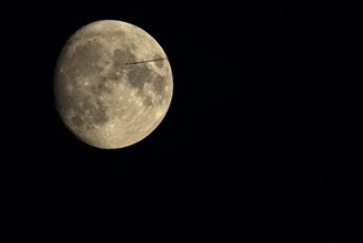 Moon with passing jet
