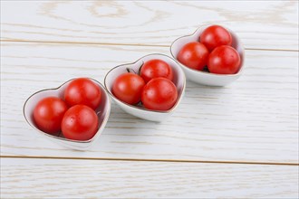 Red ripe cherry tomatos tomatos in heart shaped bowl
