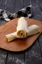 Rolled pita on wooden board with a napkin on a table