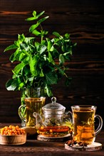 Low key photo of hot herbal tea with sea buckthorn and mint on wooden table