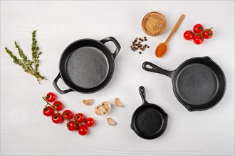 Cast iron skillets and spices on white wooden culinary background