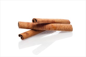Three cinnamon sticks with reflection on white background