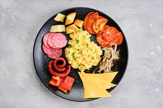 Top view of a plate with scrambled eggs with various sausages