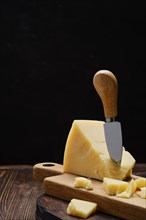 Triangular piece of parmesan cheese on wooden cutting board