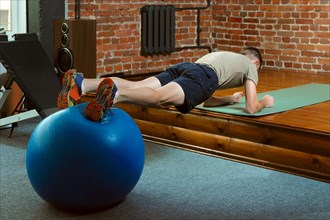 Athletic man doing balancing exercises with the gym ball. Fitness workout