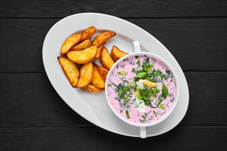 Overhead view of cold beet soup with potato wedges on a plate