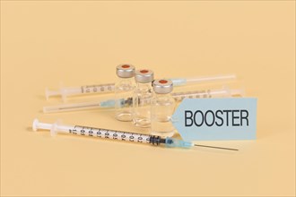 Concept for Corina virus booster vaccination with 3 vials and syringes on yellow background