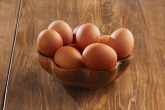 Wooden plate with raw eggs on a table