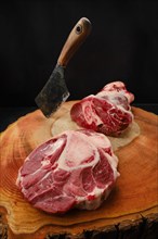 Chopping ossobuco steak from beef shank with cleaver on wooden stump