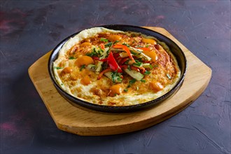 Vegetarian omelette with vegetables in cast iron pan