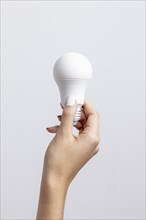 Front view hand holding light bulb with copy space