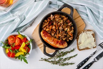 Cast-iron pan with fried sausage and mushrooms