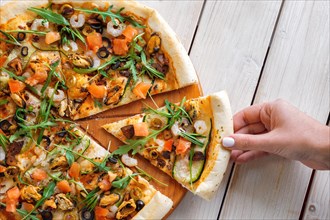 Hand picking slice of pizza with shrimps