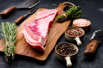 Fresh raw lamb breast and flap on wooden cutting board with herbs and seasoning