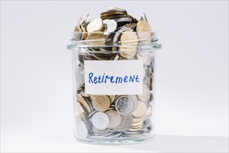 Retirement glass container full coins white backdrop