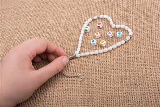 Heart shaped object in hand by a praying beads on canvas