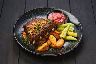 Juicy grilled pork ribs with potato wedges and cucumber