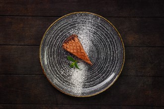 Top view of plate with piece of chocolate cake on wooden background