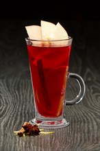 Glass of hot fruit tea with apple and anise on wooden table