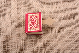 Paper arrow and Islamic Holy Book Quran in mini size