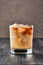 Iced coffee with fat cream on dark wooden background