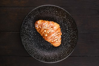 Top view of freshly baked big croissant with caramel on a plate