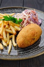 Close up view of Kiev cutlet with american fries and red cabbage with carrot as a garnish