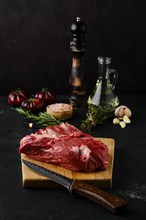Raw beef top round roast with spices on dark background