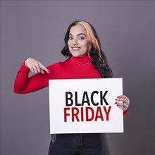 Beautiful woman pointing at a Black Friday sign. Commercial concept. Commerce