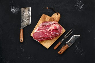 Overhead view of raw lamb shoulder without bone on wooden cutting board